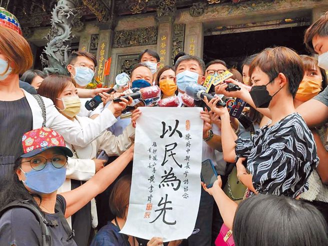 台北市長參選人陳時中20日前往龍山寺參拜，龍山寺贈送「以民為先」字畫。（郭吉銓攝）