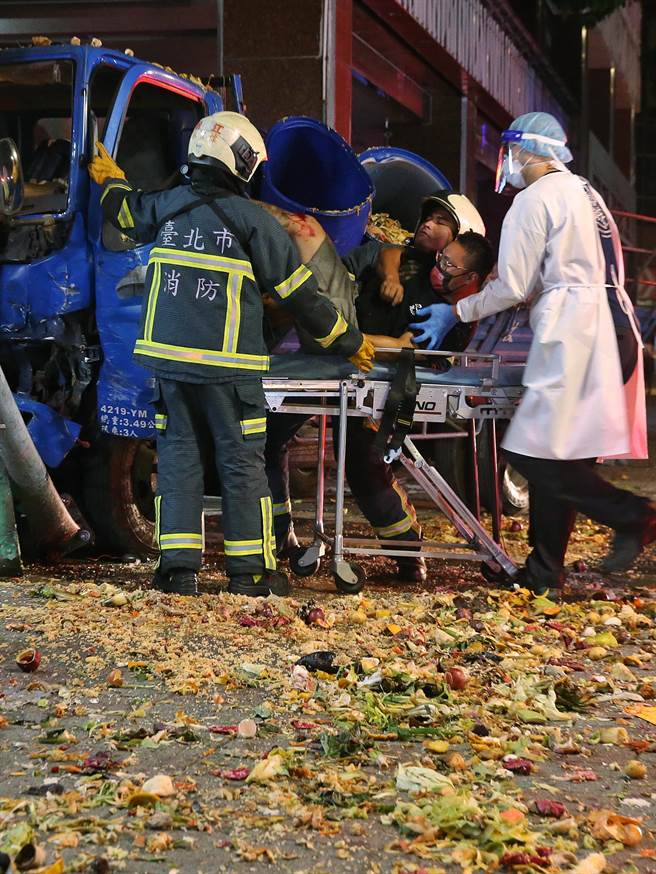 消防人员踩过满地残渣油水将张姓驾驶抱至担架上。（杜宜谙摄）