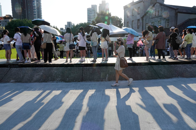 今「大暑」，全台飙高温，待在户外的民眾撑伞遮阳。（黄子明摄）