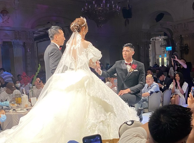 周柏臣採取跪姿从岳父手上接过老婆的手。(黄及人摄)