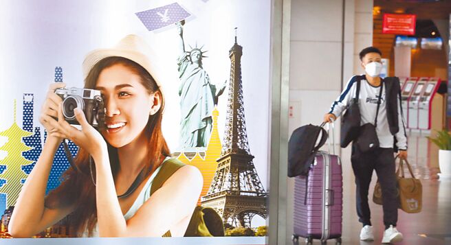 交通部观光局23日表示，将邀请日本旅游业界踩线团来台参访。图为桃机第一航厦出境大厅内，走过广告灯箱的旅客准备办理登机手续。（范扬光摄）