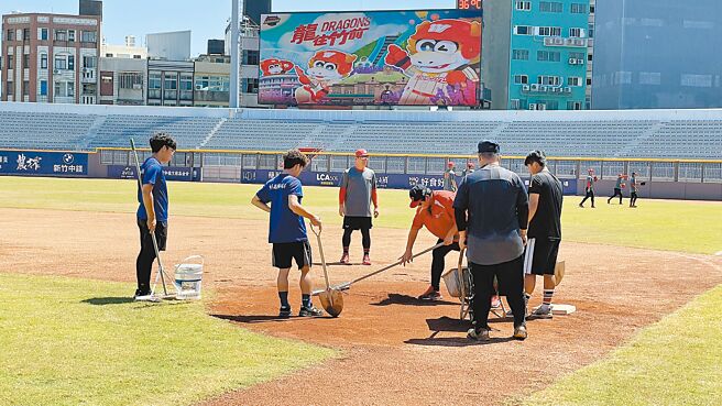 斥资12亿全新改建的新竹棒球场，多数球员、教练都反映内野红土太过松软的问题，赛前龙队总教练叶君璋（红衣者）亲自整理场地。（毛琬婷摄）