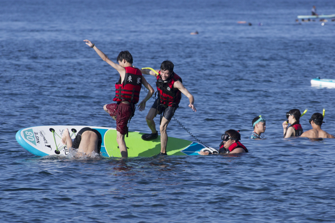 全台连日气温飙升，到海边戏水成为许多人的首选，新北境内的鼻头角、龙洞海边挤满人潮，年轻人在海上玩起近年流行的立桨，顺便来个角力赛，结果大家纷纷落海。（黄子明摄）