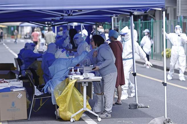圖為今年5月上海民眾在市區臨時核酸檢測採樣點進行採樣。（摘自中新社）