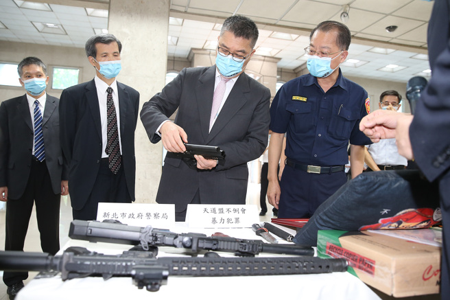 内政部长徐国勇（中）27日前往刑事局出席「全国同步扫黑行动专案」成果记者会，并拿起扫黑肃枪行动中查缉到的枪械观看。（姚志平摄）