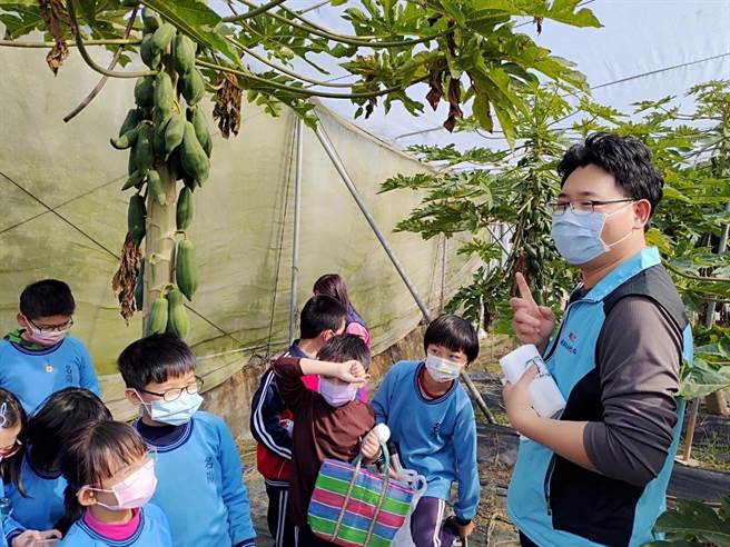 林浚宇（右一）向參觀學童，解說他種植木瓜的方法與半自動化監測管理。（南投縣政府提供）