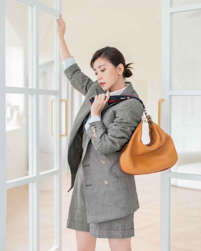 賈靜雯以淺灰色格紋西裝搭配Gucci Attache 琥珀色中號肩背，展現俐落都會女性形象。（Gucci提供）