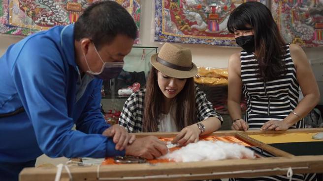 中华文化总会「福尔摩沙进香团」计画影片推出第4集，由来自泰国的蓝星（Christine Lan/ YatikaVajropala中）担任领旗人，前往台南探访台湾的传统宫庙文化。图为蓝星亲手体验宗教闽绣。
（图/ 中央社）
