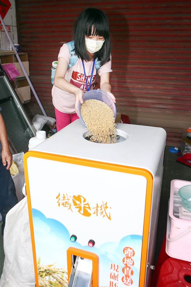 一位小朋友起个大早前往北投体验「2022北投割稻趣」碾米程序。（邓博仁摄）