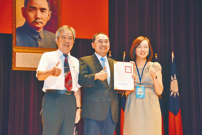 新北市昨日举行新卸任校长交接典礼，淡水国中新任校长王洁雯与曾任多届校长的父亲王仁宏一同上台，接受新北市长侯友宜表扬。（蔡雯如摄）