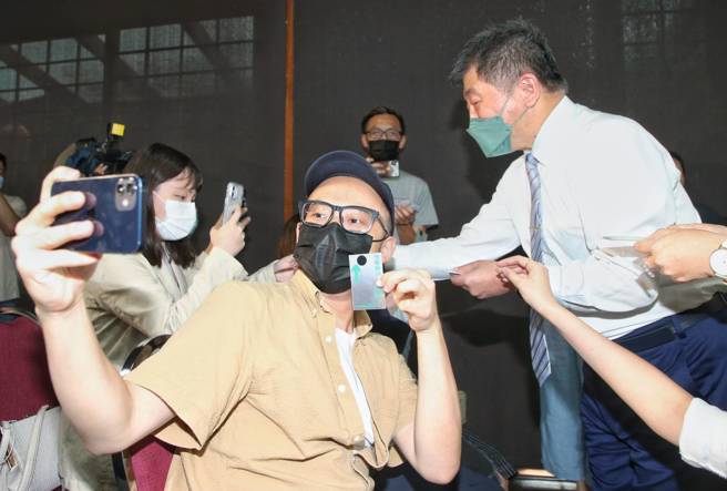 民进党台北市长参选人陈时中（右）30日公布竞选主视觉出炉，由儿子陈彦安团队操刀设计，以三个符号分别象徵沟通、进步与团结，希望成就更好的台北，并亲自向媒体发送印有主视觉的新名片。（赵双杰摄）