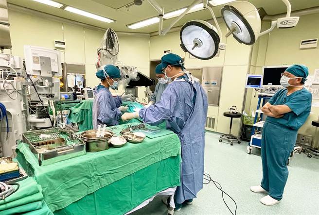 许权振副院长（右立）全程见证，台中慈院第300例人工电子耳手术。（台中慈济医院提供）