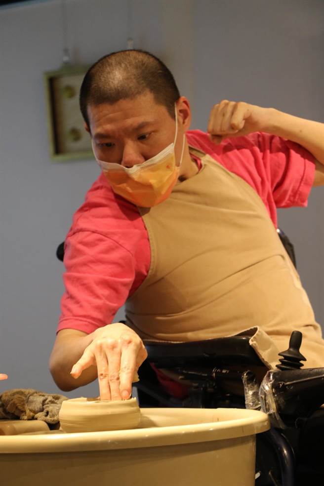 新北市立八里爱心教养院院生阿琮全神贯注以「黄金右手」拉出浅碟花器，左手则紧绷蜷握扬起。（新北市社会局提供）