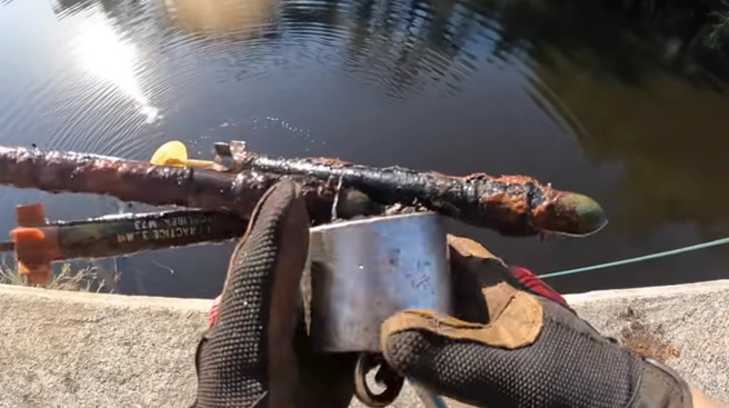 美国「磁铁钓客」在史都华要塞附近的河流，捞出火箭弹等武器。结果遭军方罚款。(图/Youtube)