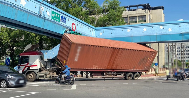 桃园货柜车行经桃园医院路口时，未注意天桥高度限制，转弯时车身卡在天桥下。（图／翻摄自桃园都）