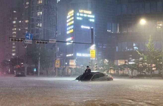 首爾暴雨淹大水，西裝男慘被困車頂，照片引網瘋傳。（圖／翻攝推特@lora5102）