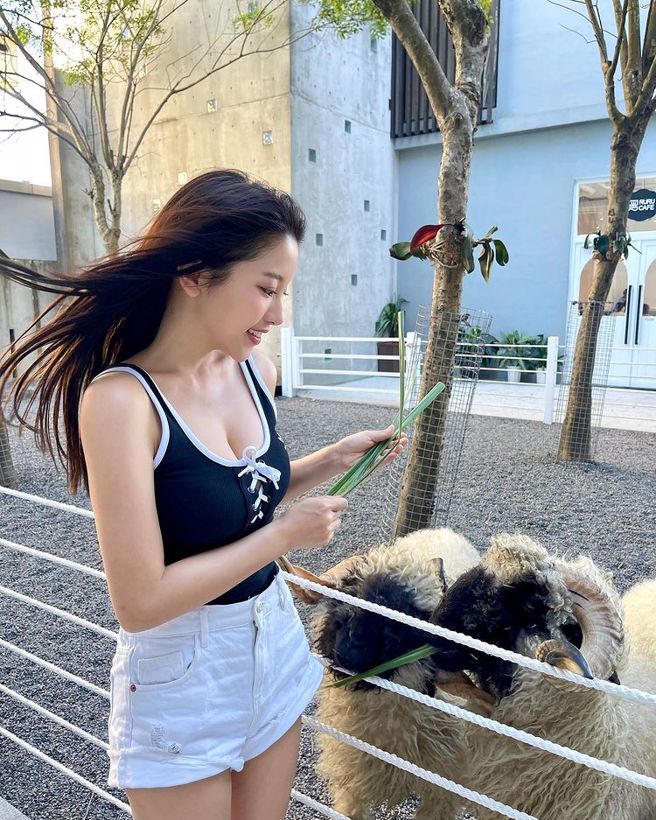 蔡瑞雪穿着蓝布鞋绑带上衣，拿牧草喂羊模样俏皮性感。(图/蔡瑞雪 IG)