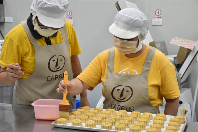 近日訂單陸續進來，憨兒們精神百倍，每個人聚精會神做好自己的工作，圖為憨兒接受老師指導在月餅上抹蛋液。（林雅惠攝）