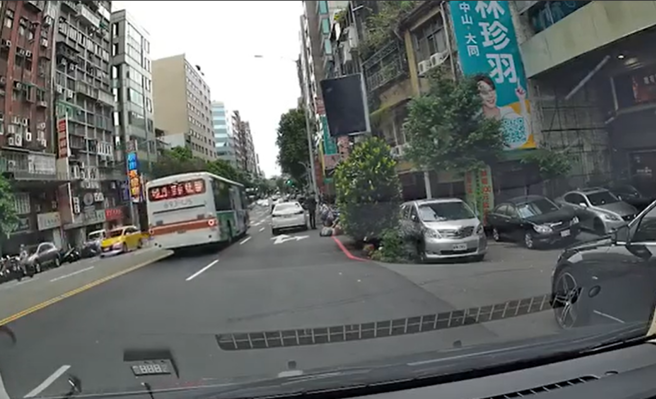 白车驾驶在路边准备行驶时，突然车身震动一下，竟是辗过1名「躺在路边」的民眾，该民眾遭辗后马上蜷缩身体，看似很痛苦，车主也赶紧下车查看。（翻摄自爆料公社）