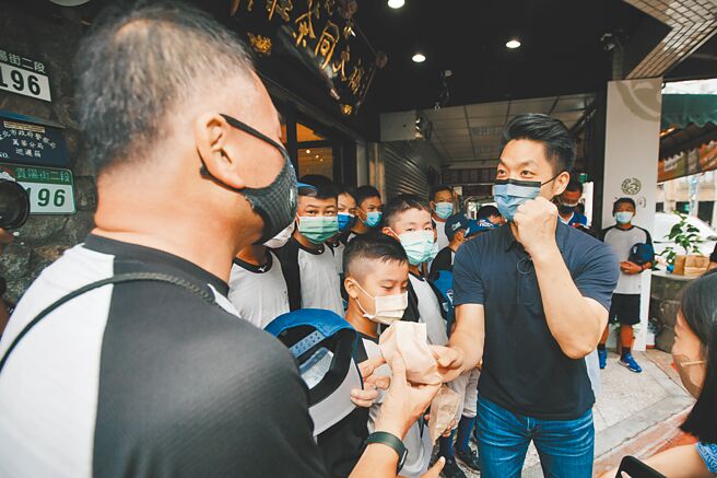 国民党台北市长参选人蒋万安（右）10日为福林国小少棒中华代表队加油打气，送上红豆饼祝贺少棒队「红不让」。（郭吉铨摄）