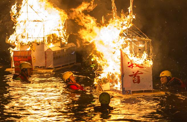 鸡笼中元祭各宗族精心制作的水灯11日傍晚在基隆市区遶境游行，午夜11点在望海巷海域施放水灯，水灯点燃后的热焰，让泡在水中协助拖行灯座的救难协会人员频频闪躲。（黄子明摄) 