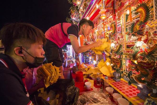 配合鸡笼中元祭 鸡笼中元祭各宗族人员将银纸、经衣等纸钱塞入水灯头，准备随着水灯烧给水上孤魂。（黄子明摄) 