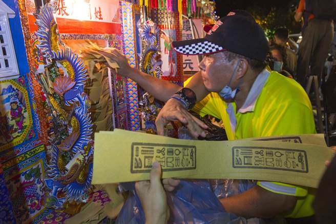 配合鸡笼中元祭 鸡笼中元祭各宗族人员将银纸、经衣等纸钱塞入水灯头，准备随着水灯烧给水上孤魂。（黄子明摄) 