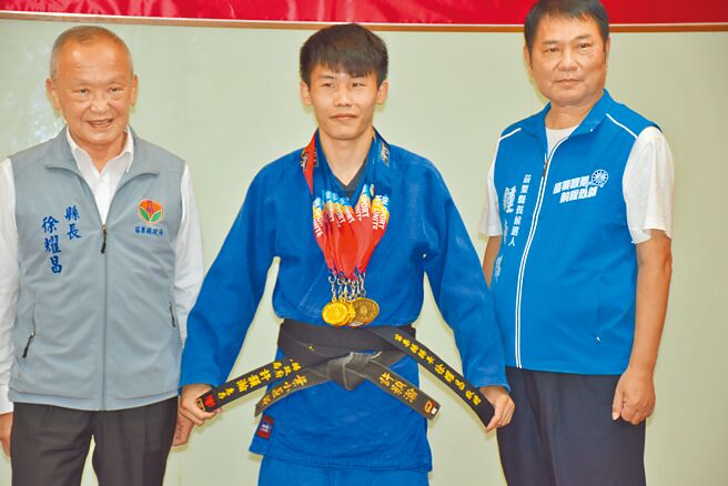 苗栗县消防局队员许颢瀚（中）勇夺世界警消运动会5金，县长徐耀昌赠送纪念腰带。（谢明俊摄）