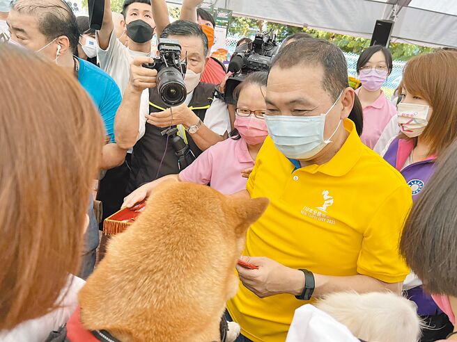 新北市长侯友宜参与「中元毛宝贝联合祈福会」，在现场参与法会的毛孩的项圈上，一一繫上平安符。（李奇叡摄）
