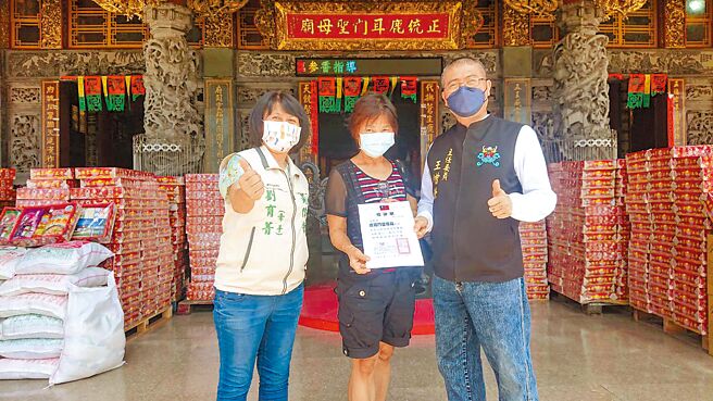 台南市长黄伟哲妻子刘育菁（左一）见证庙方主委王增荣（右一）捐赠中元节供品。（程炳璋摄）