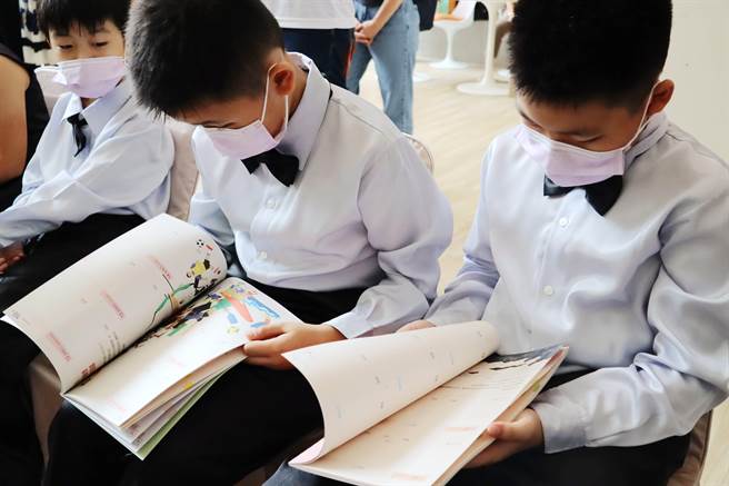 嘉義縣設計、印製「看見嘉義，美感聯繫」聯絡簿，今在記者會上，參與演出學童忍不住翻看起來，說好特別。（呂妍庭攝）