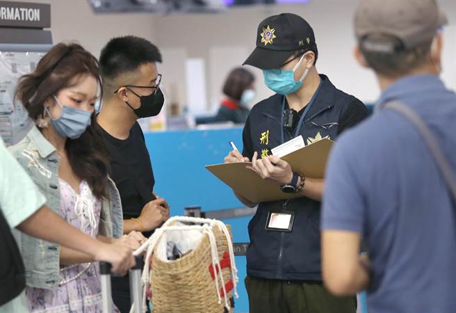 在桃園機場第二航廈出境大廳內，航警局員警在航空公司報到櫃台前，向前往柬埔寨的旅客宣導，避免有人受害。（范揚光攝）圖中非新聞當事人