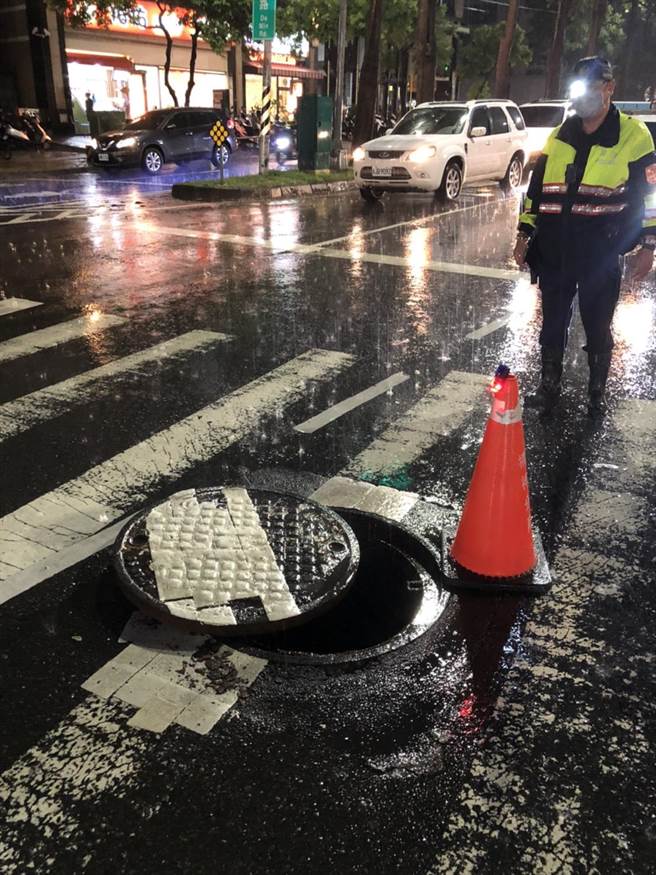 楠梓警方获报德民路与蓝昌路口的人孔盖移位，员警冒雨到场维安。（翻摄照片／林瑞益高雄传真）