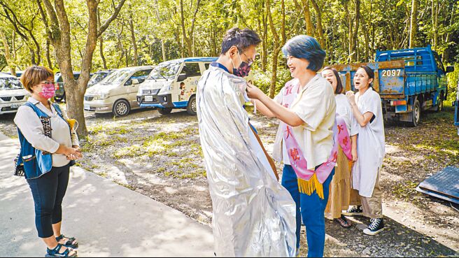 嚴藝文（右）親自替徐超斌醫師綁披風，顯得相當害羞。（桂田文化藝術基金會提供）