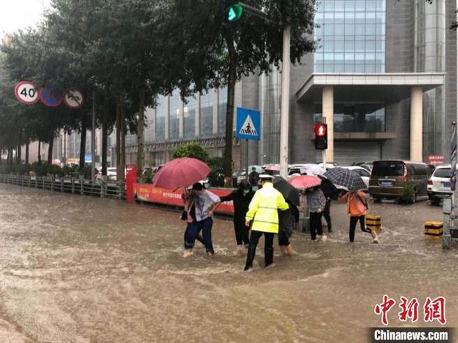 图为2020年8月29日，青海省西寧市遭遇暴雨，当地交警帮助行人过马路。（资料照／摘自中新网）