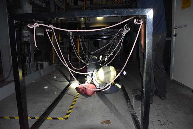 受训队员模拟在全黑火场中通过各种障碍。（谢明俊摄）