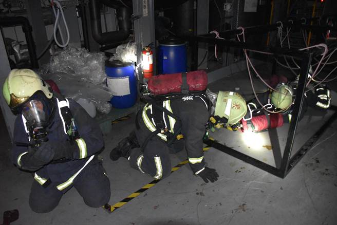 受训队员模拟在全黑火场中，相互协助通过各种障碍。（谢明俊摄）