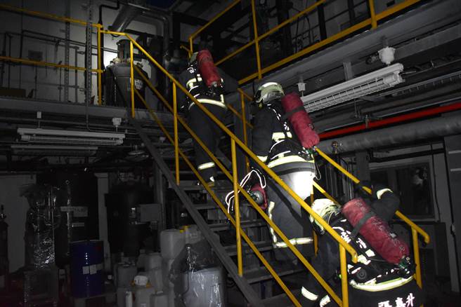 受训队员模拟在全黑火场中通过各种障碍上楼搜救受困队员。（谢明俊摄）