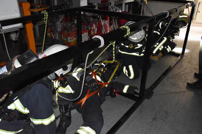 快速援救小组找到受困队员，以束带将昏迷队员拉出火场。（谢明俊摄）