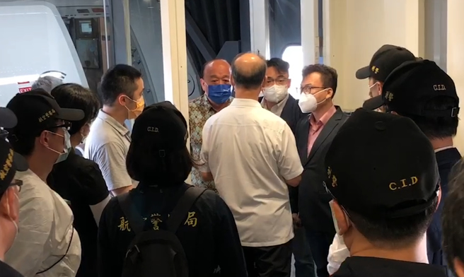 国民党立委吴斯怀（后左）、洪孟楷（后中）及郑正钤（后右）18日带着1名受困柬埔寨的男子搭机抵台，下机时3名立委认为，航警局企图将被害人直接从机坪带走手法过于粗暴，因此在空桥上与警方争论不休。（立委提供）