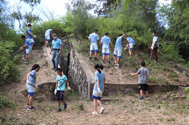 賢庵國小和臺中市明道高中學學生合力移除退役彈藥庫上的外來種植物。（金門縣林務所提供）