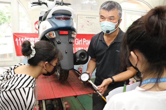 新北高工汽车科老师邱传福教导女孩如何正确打气并量胎压。（新北市社会局提供）
