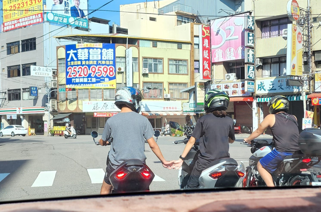 1名网友等红灯时，突见前方骑士手牵手秀恩爱，让他不禁发文直呼：「闪瞎单身狗的眼睛」。（图／路上观察学院）