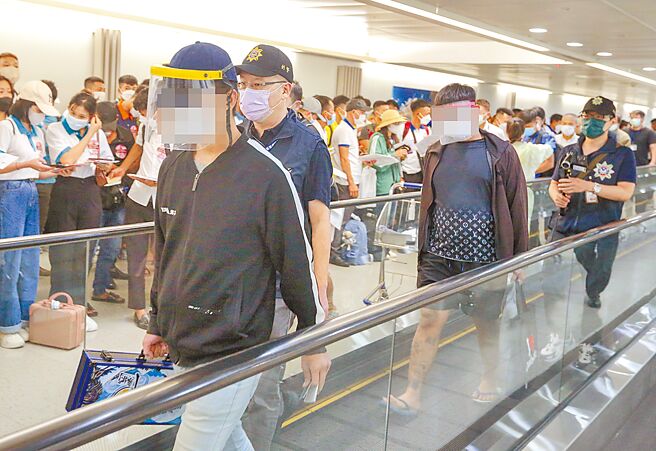 原本滯留柬埔寨未歸的18歲鄭姓男子於21日下午搭機回台，機上除了鄭姓青年外，還有另外一名張姓關係人也搭乘同航班一同抵台。張姓關係人（右二）身穿印有「LV」花紋T恤，手提印有「我愛柬埔寨」英文字樣的提袋，顯得格外諷刺。（陳麒全攝）