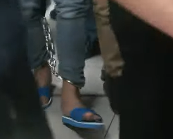 涉杀警员的凶嫌林信吾23日上午押抵台南警第三分局，手脚均上铐，低头不语。（翻摄自中时新闻网直播）