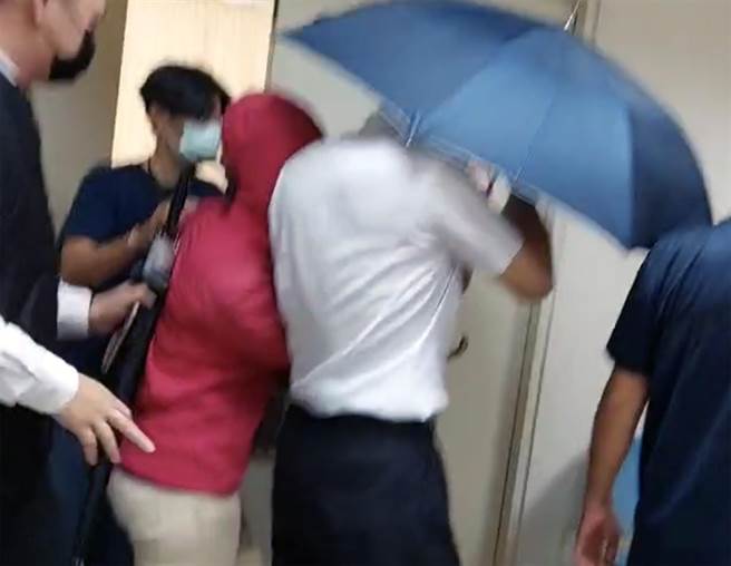 殉职警员凃明诚的姊姊，在警方动用「伞阵」的保护下，接受检方讯问。（洪荣志摄）