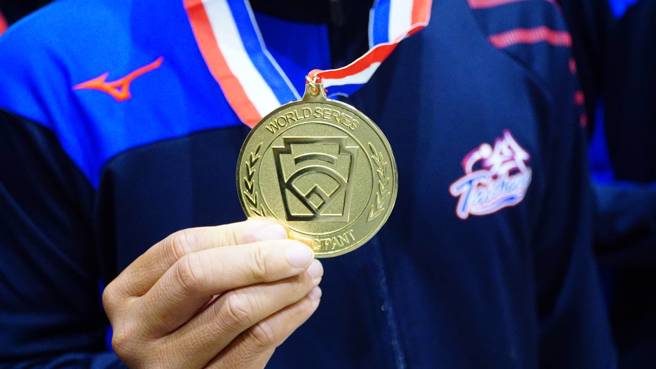 台中市中山国中棒球队队员展示LLB次青少棒世界冠军奖牌。（台湾世界少棒联盟提供）