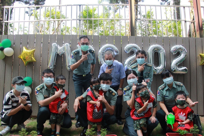 家长带着身着「迷彩套装」的孩子一同体验幸福植栽活动，不仅增进亲子互动，也让学童家长进一步认识教保中心环境，现场气氛热闹温馨。(军备局提供)