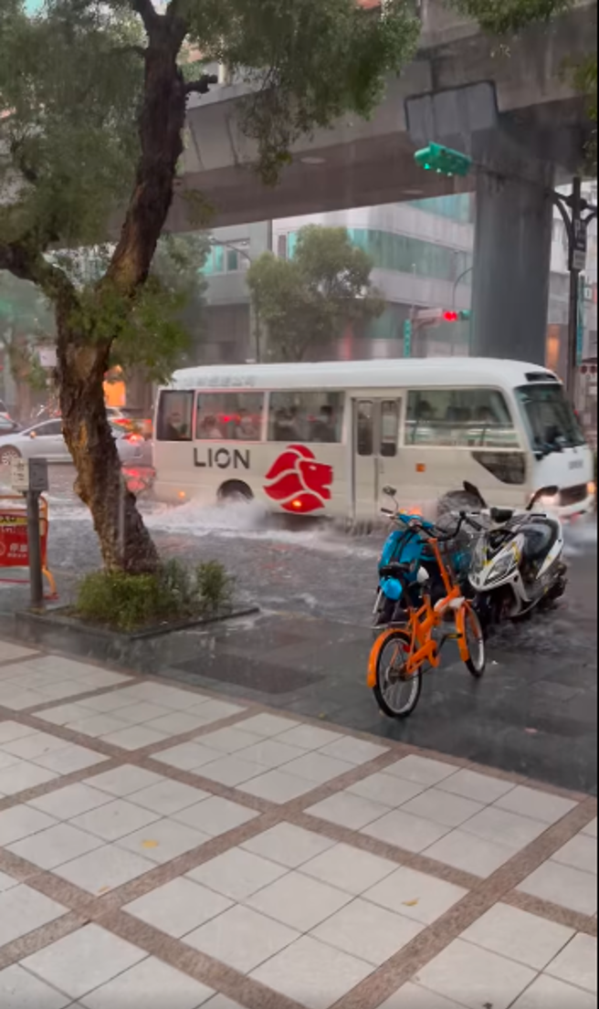 六張犁捷運站附近汽、機車涉水而過，行徑處濺起不小水花。（圖／臉書「信義區三兩事」）
