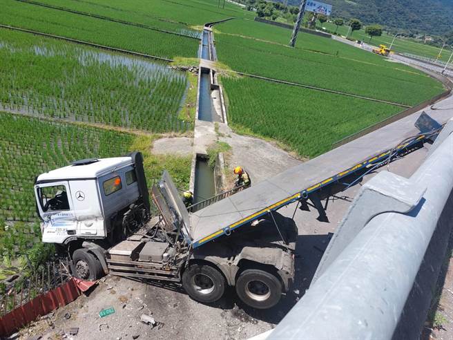 滿載貨物的拖板車，在上橋過彎路段，不明原因失控，整輛車衝出護欄，車頭掉落十多公尺的橋下，車身則還卡在橋上。（警方提供）